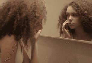 mulher analisando o rosto no espelho para identificar os tipos de pele